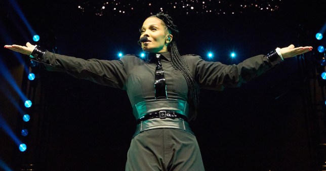 Janet Jackson with her arms outstretched on stage 