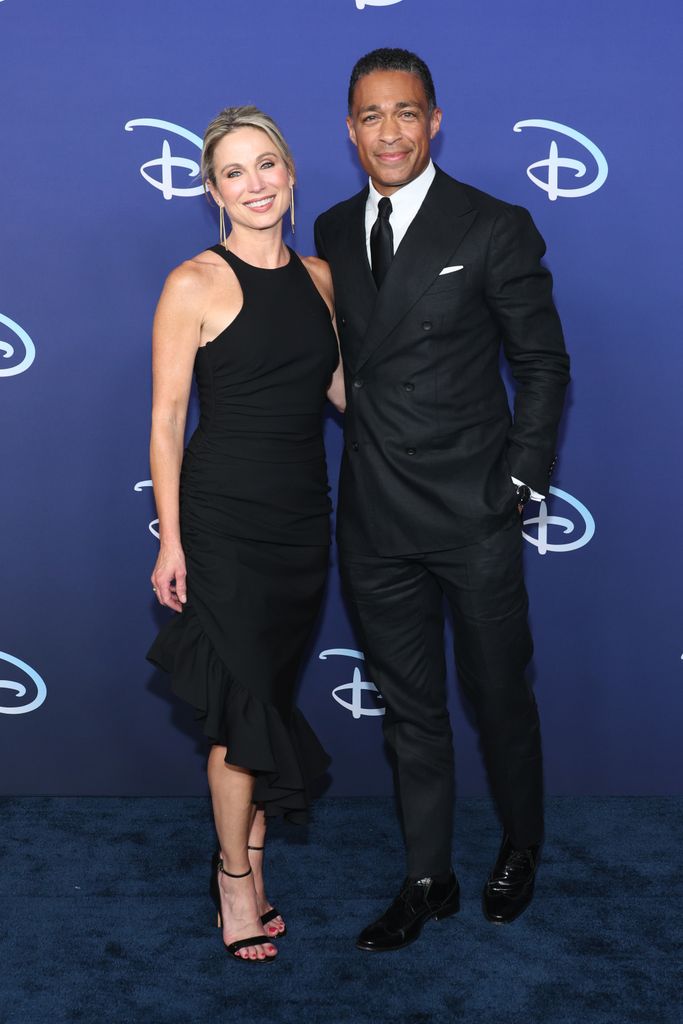 Amy Robach in a black dress and TJ Holmes in a suit