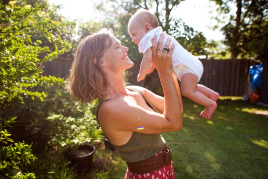 A mum holds her baby in a backyard