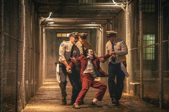 Joker being dragged away by prison guards into Arkham Asylum