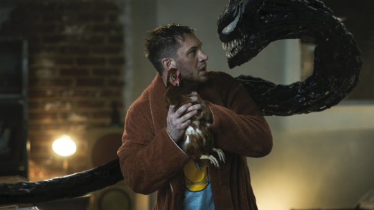 Tom Hardy as Eddie Brock in Venom 2 –aka Venom: Let There Be Carnage – looking nervously at Venom who snakes around him