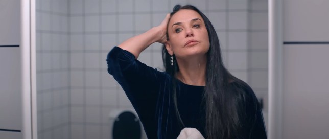 Demi Moore as Elisabeth Sparkle in The Substance. She is examining her face in the bathroom mirror