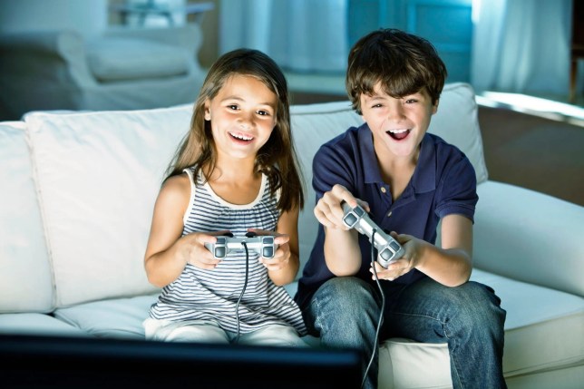 Two children playing console video games on a couch