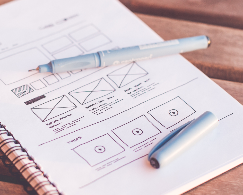 A sketchpad with a pencil showcasing wireframes for modern digital prototypes, a key element in the work of Business Developer and UX Designers.