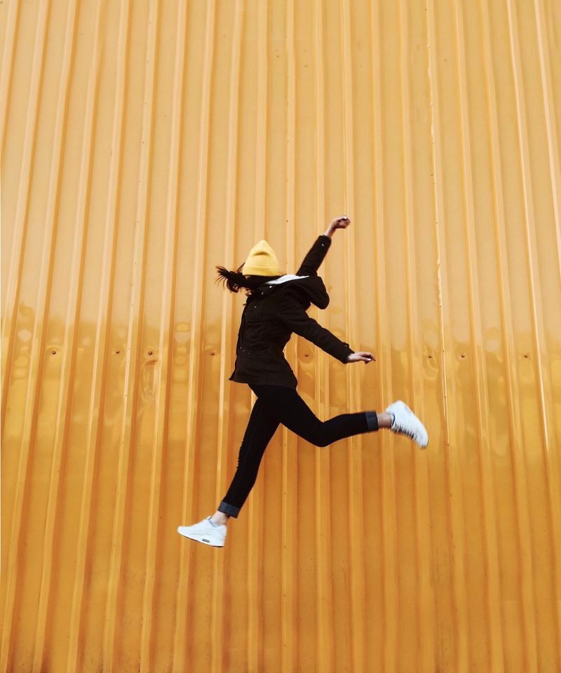 Girl is jumping on the yellow background