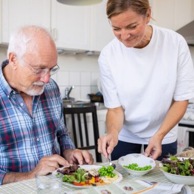 man i rutig skjorta som blir serverad mat av en kvinna i vit t-shirt