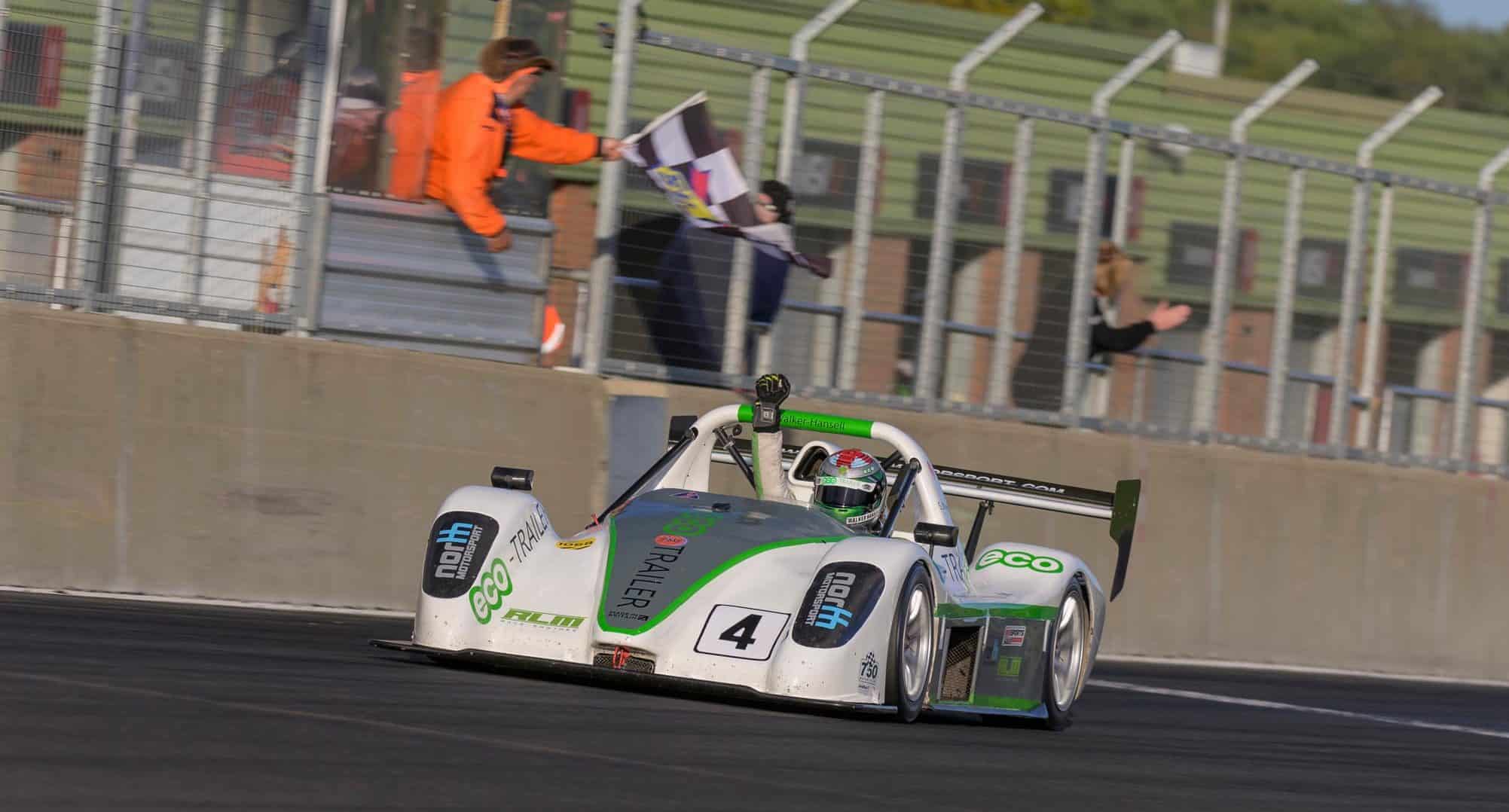 A racing car with the driver punching the air with joy.