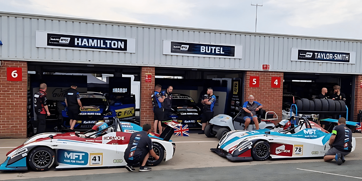 The North Motorsport Team standing in front of a building with cars
