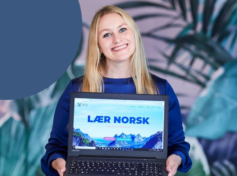 Karense Foslien holder en laptopp hvor det står "Lær norsk".
