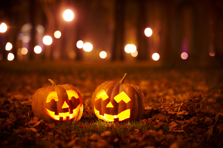 To Halloween-gresskar på bakken og lys i bakgrunnen