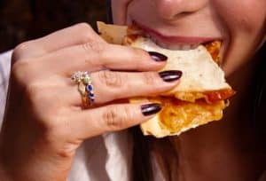 Mujer comiendo una porción de pizza