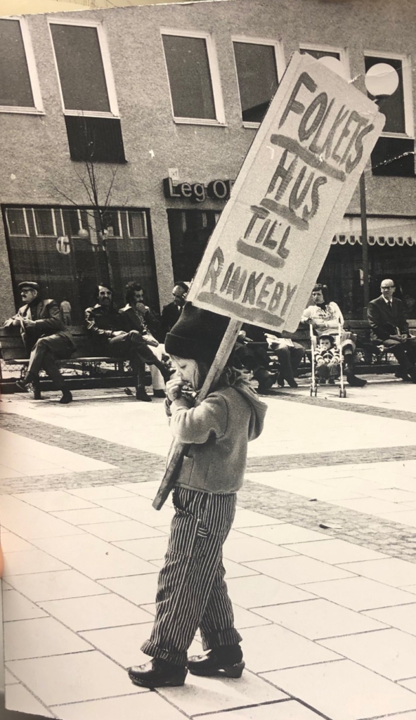 Litet barn bär på ett plakat med texten Folkets Hus till Rinkeby.