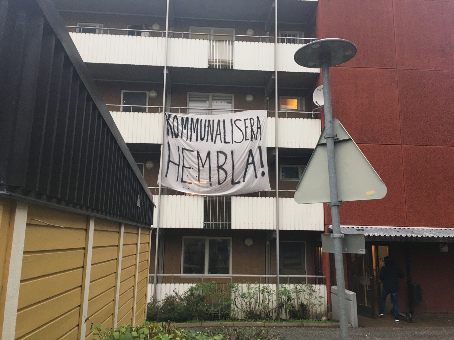 banderoll med texten "kommunalisera hembla" hänger från balkong