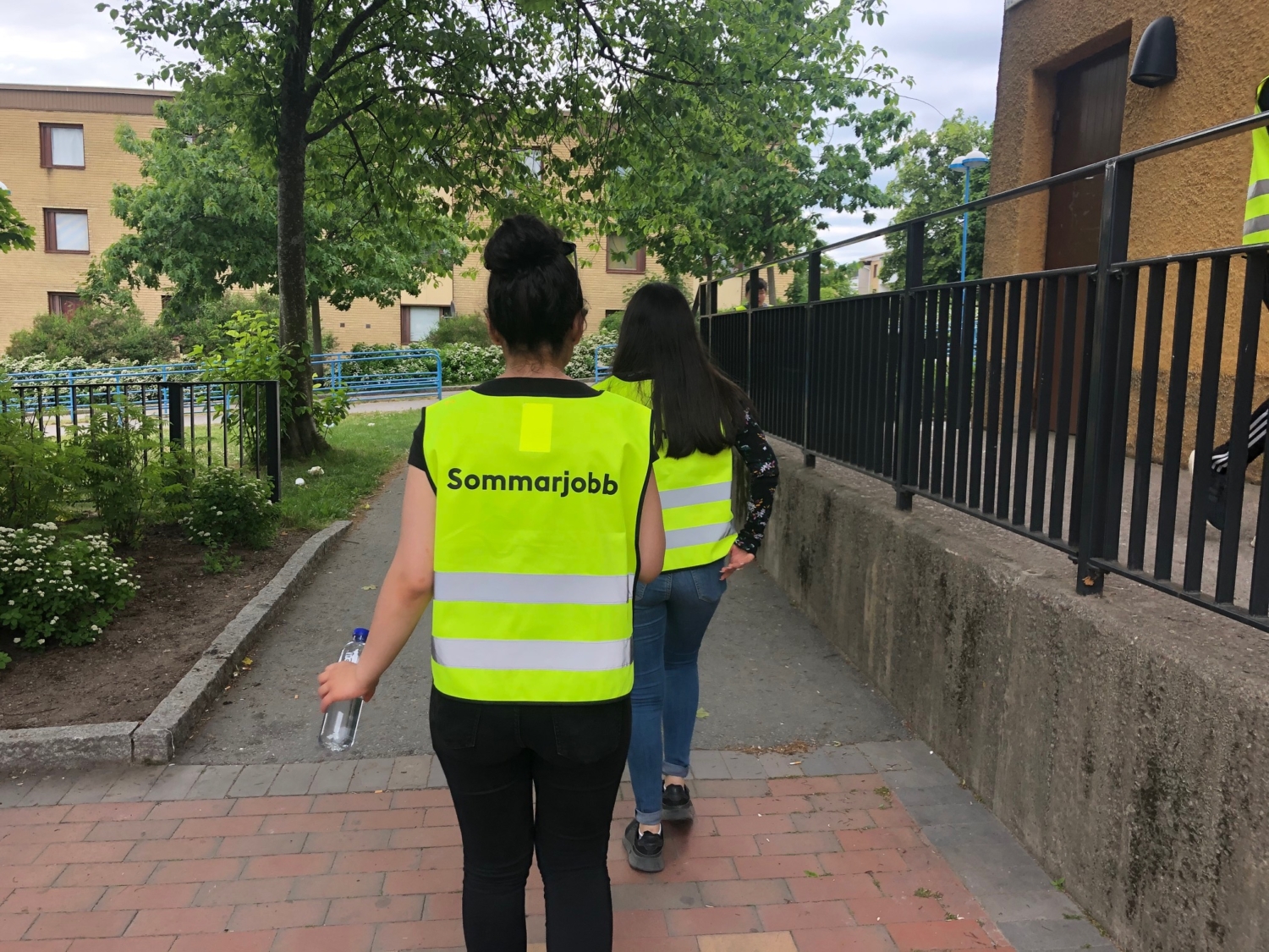 två tjejer i gula västar med texten sommarjobb