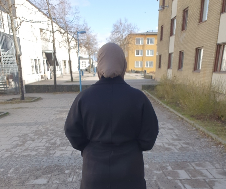 Kvinna i hijab fotograferad bakifrån.