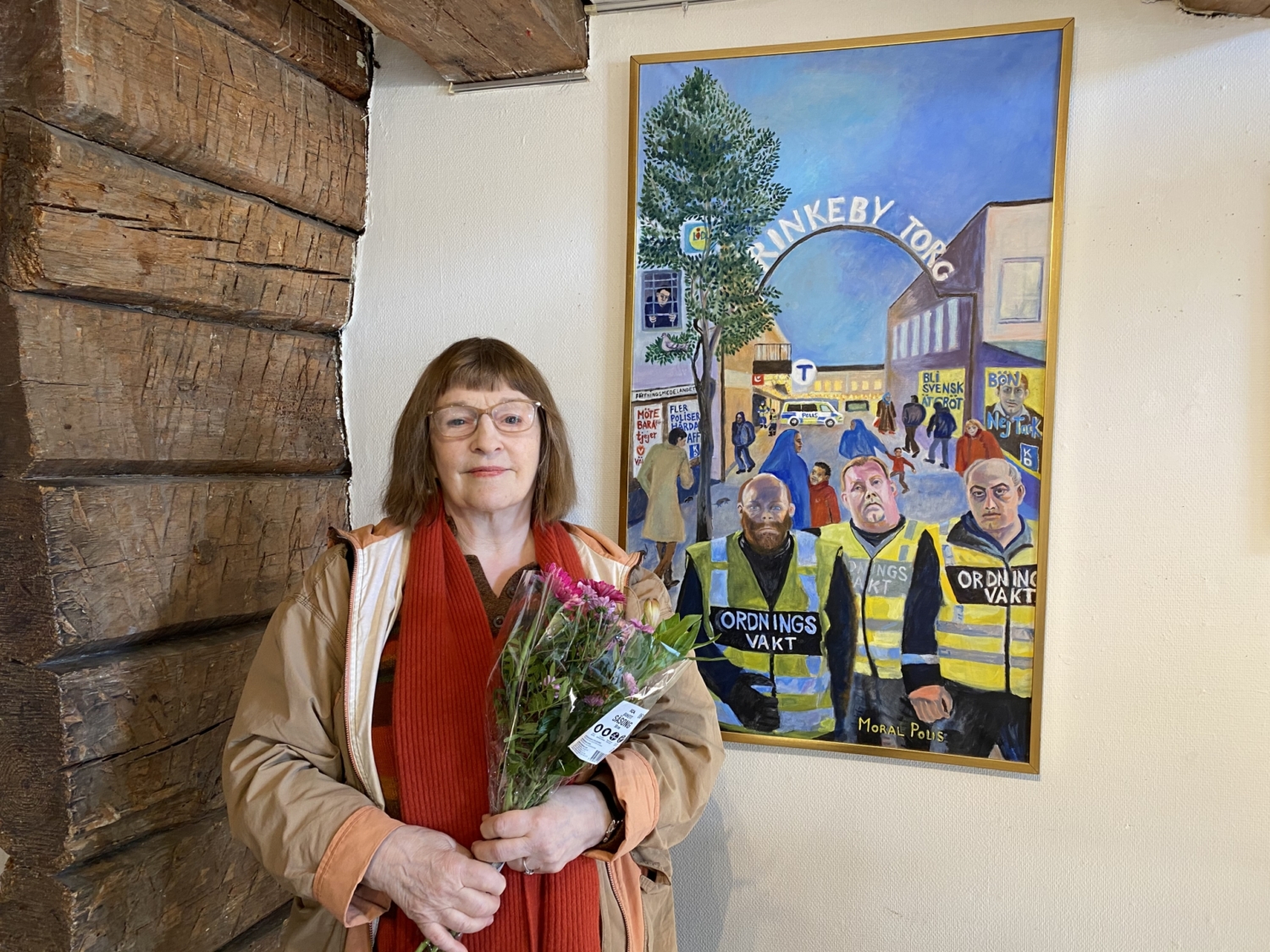 Dine Malmsten står framför ett av sina kostverk och håller i en bukett blommor.