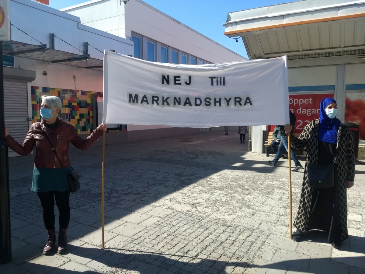 Två kvinnor med munskydd håller en banderoll med texten Nej till marknadshyra