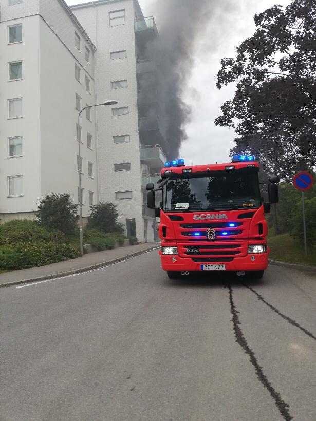 Brandbil framför ett hus och brandrök