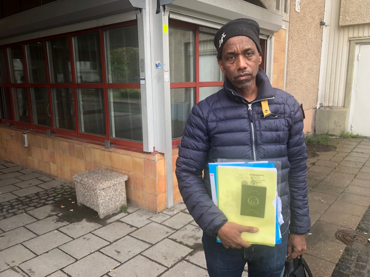 Eritreansk man med en massa dokument i handen.