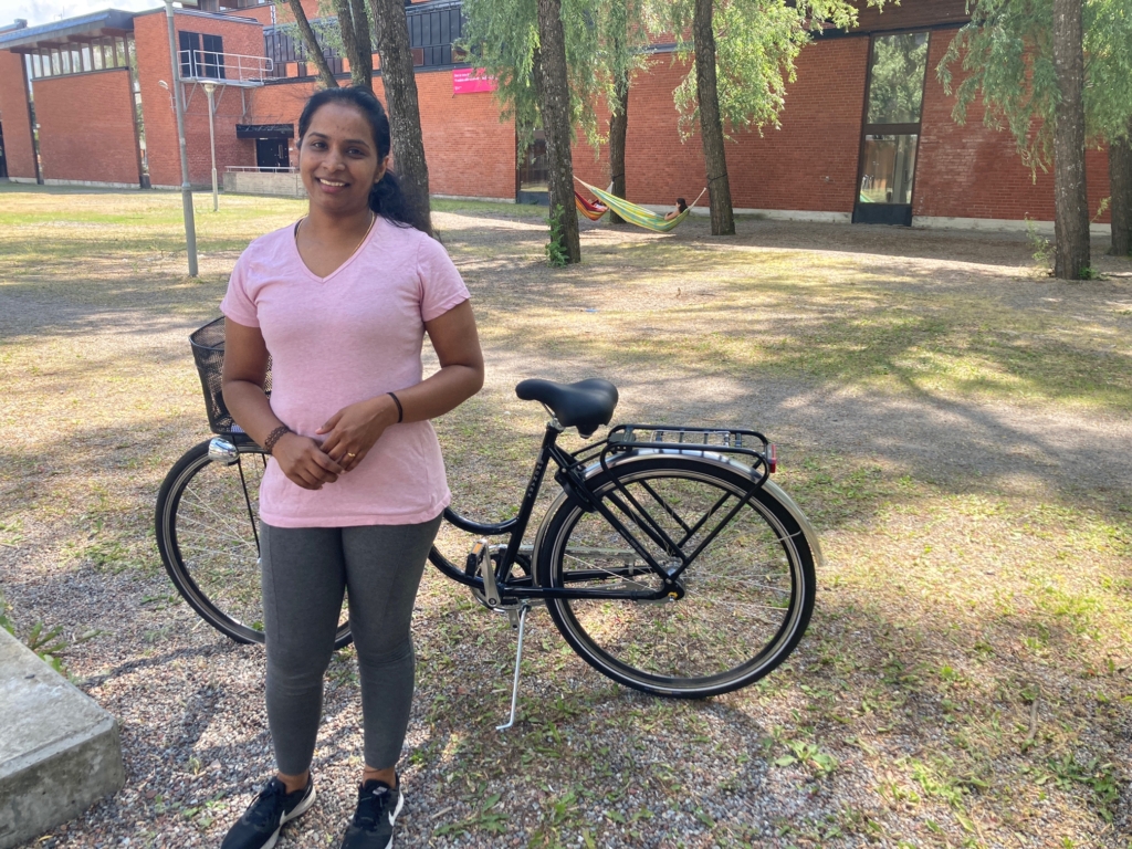 Leende kvinna framför en cykel.