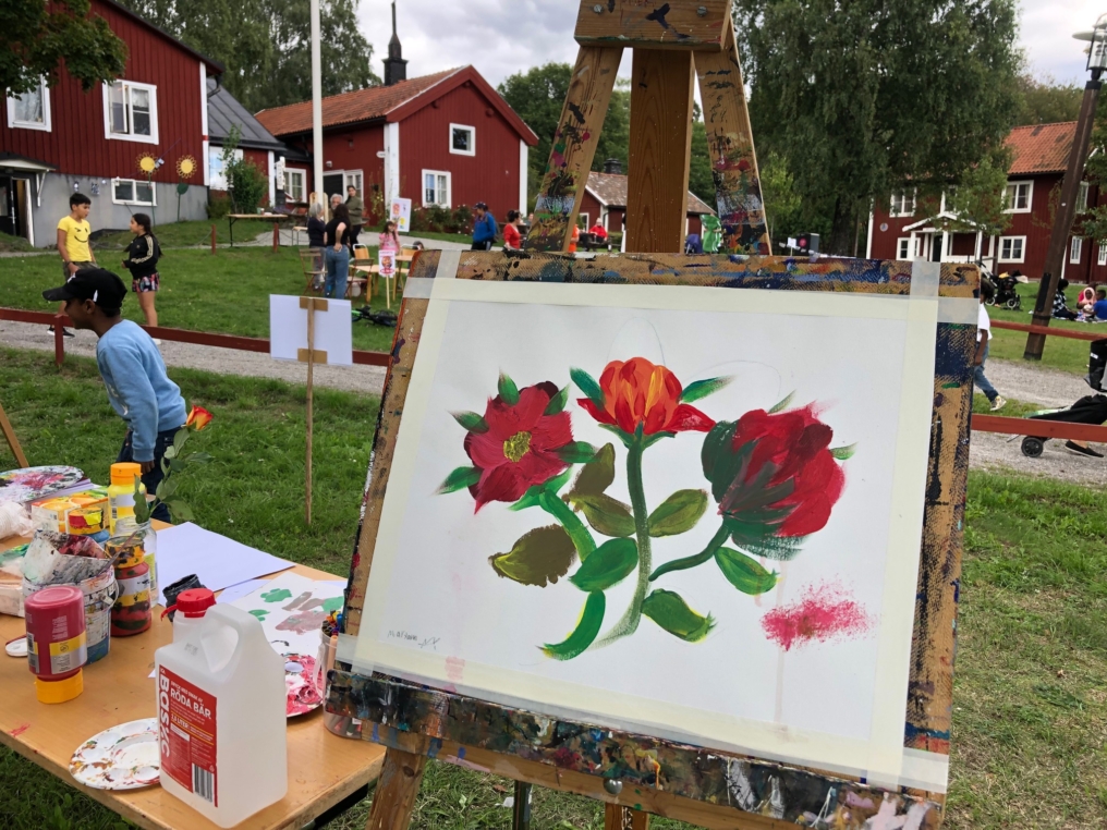 tavla med blommotiv på staffli framför husby gård