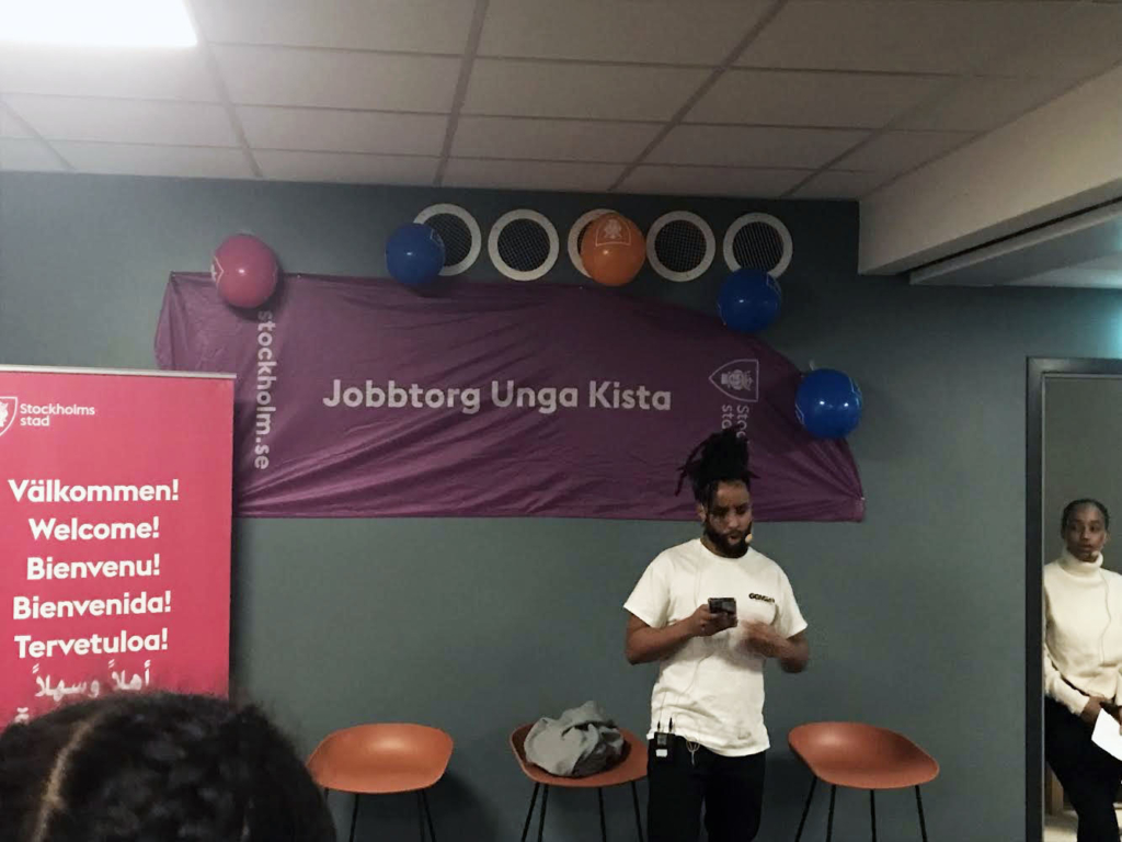 ung man framför ballonger och banderoll med texten "jobbtorg unga kista"