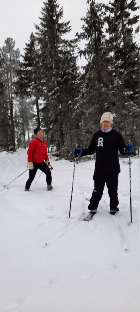 två skidåkare framför granar