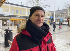 man i röd jacka småler på rinkeby torg