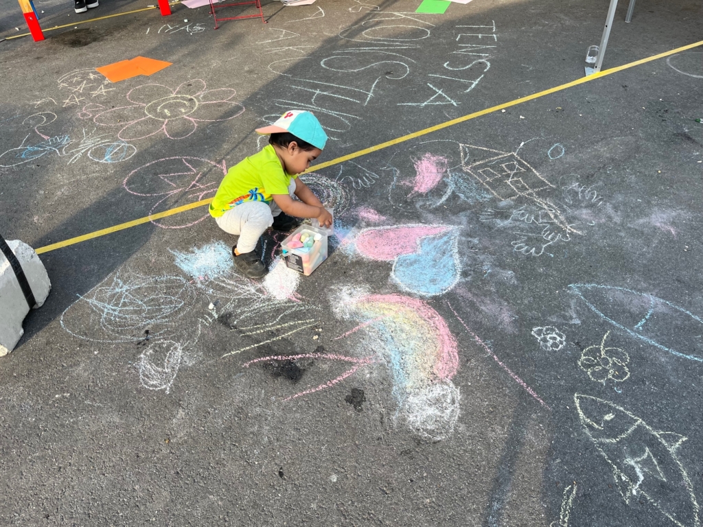 Litet barn ritar på marken.