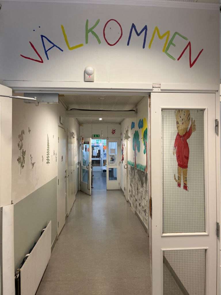 En korridor i en förskola, ovan dörren står det Välkommen.