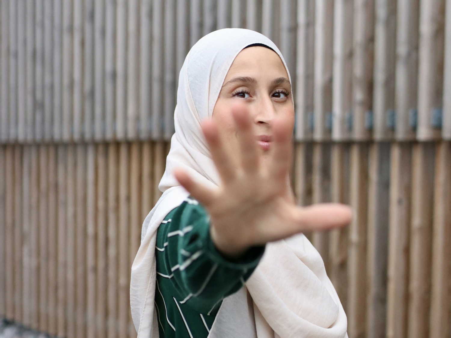 Kvinna i hijab sätter upp handen som ett stopptecken.