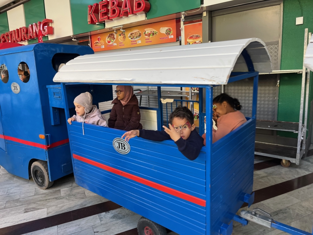 Barn som åker ett litet tåg runt i Tensta centrum.