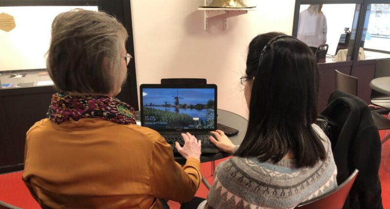 En äldre kvinna och en yngre sitter tillsammans framför en laptop