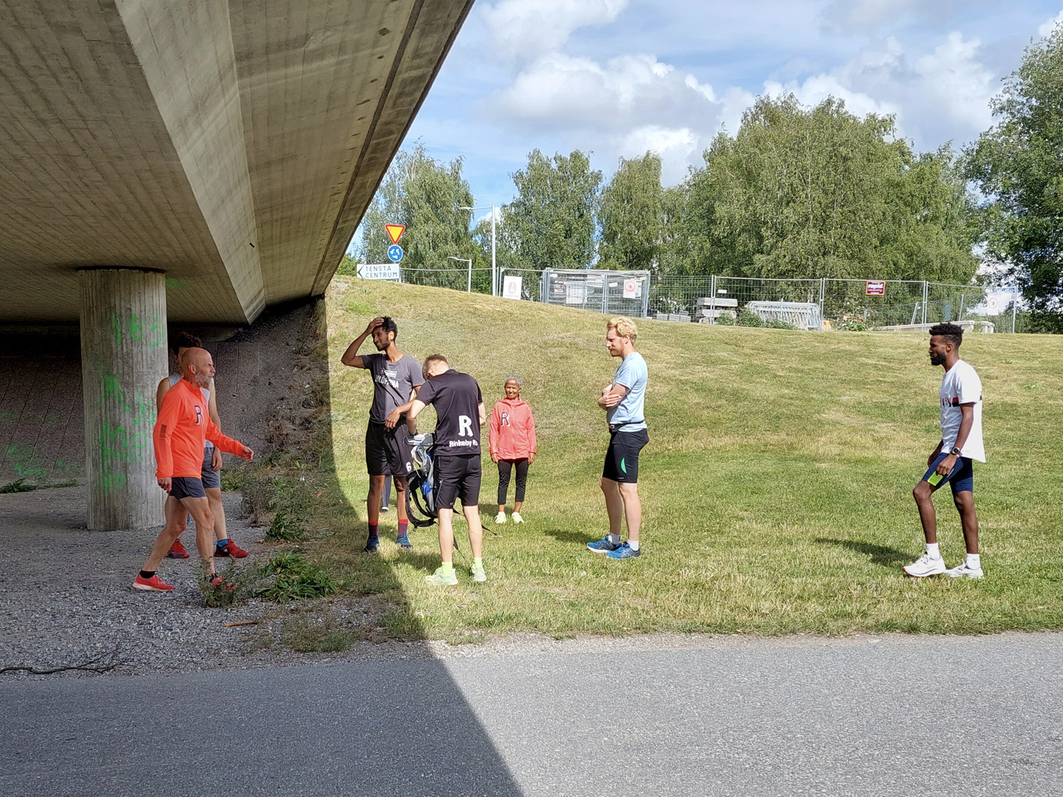 människor i träningskläder på ett gräsfält vid en gångtunnel