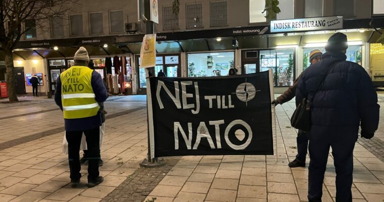 Två personer på Rinkeby torg håller i en banderoll med texten Nej till NATO.