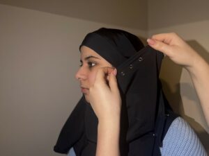 bild på kvinna som får hjälp av en annan att ta på sig sin hijab