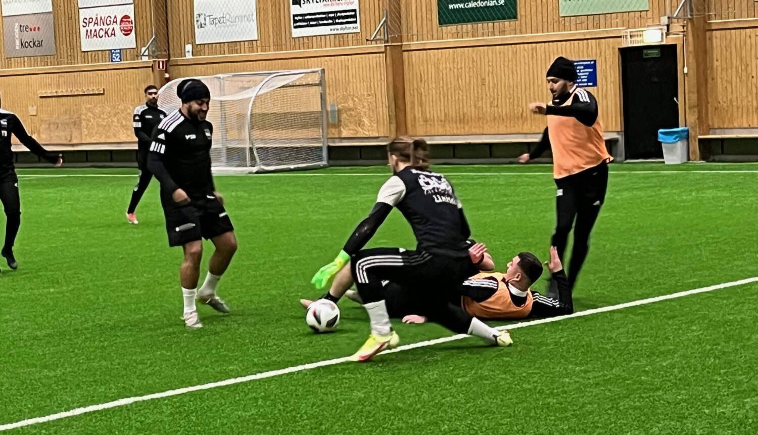 fotbollsspelare i närkamp på en konstgräsplan.