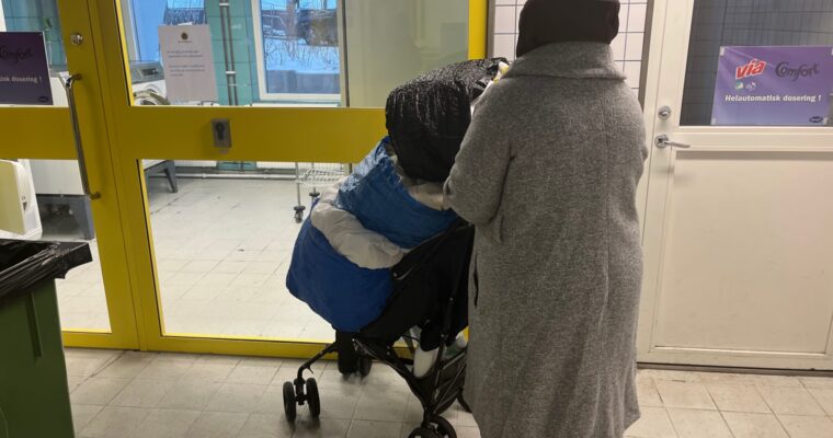 Kvinna med barnvagn full med kassar tvätt.