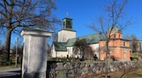 Spånga kyrka utifrån, strålande sol och knallblå himmel.