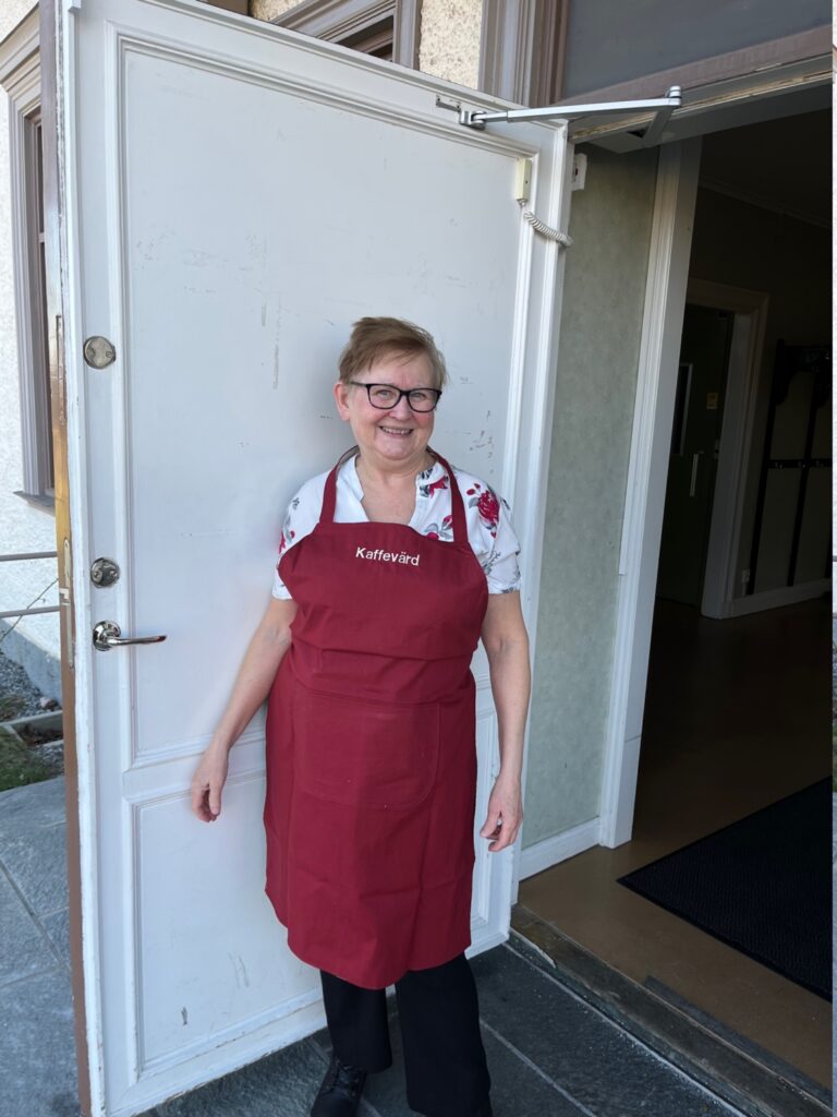 Kaffevärden Mari Källman tar emot i dörren till prästgården.