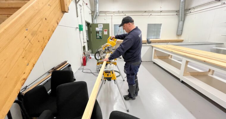 hantverkare Lars Asp sågar i en planka i fritidsbiblioteket