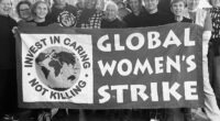 En svartvit bild med många människor bakom en banderoll. Texten Global Women's strike.