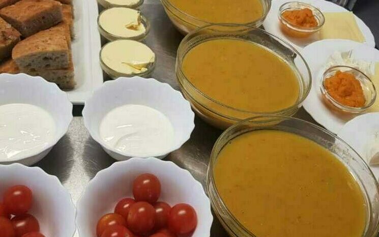 soppa, bröd och grönsaker i skålar