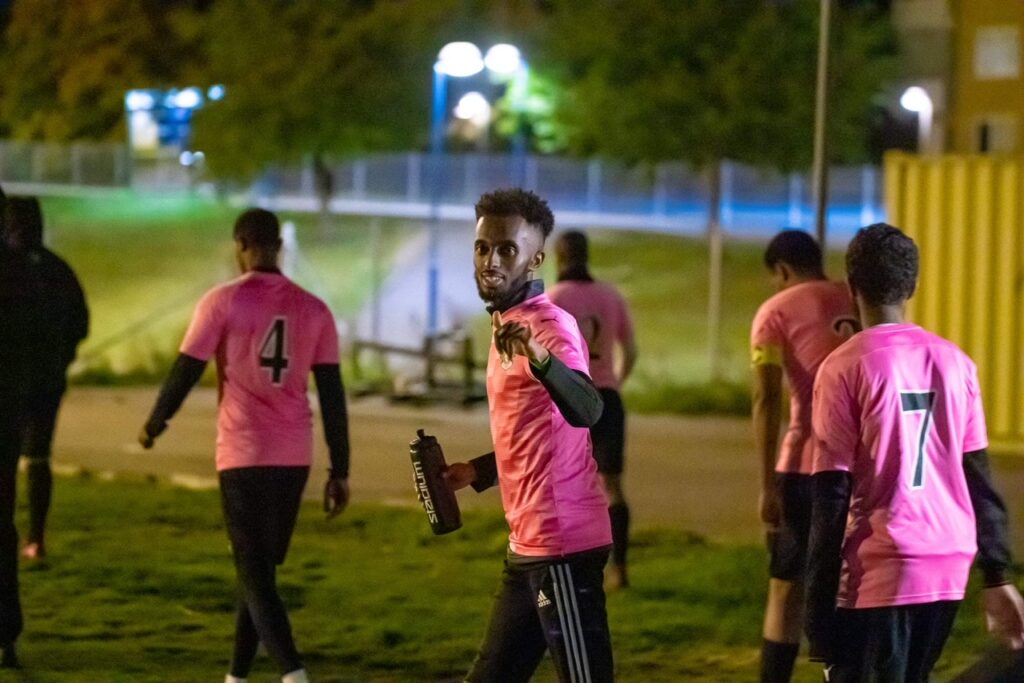 Fotbollsspelare i rosa matchställ, en kille kollar in i kameran.