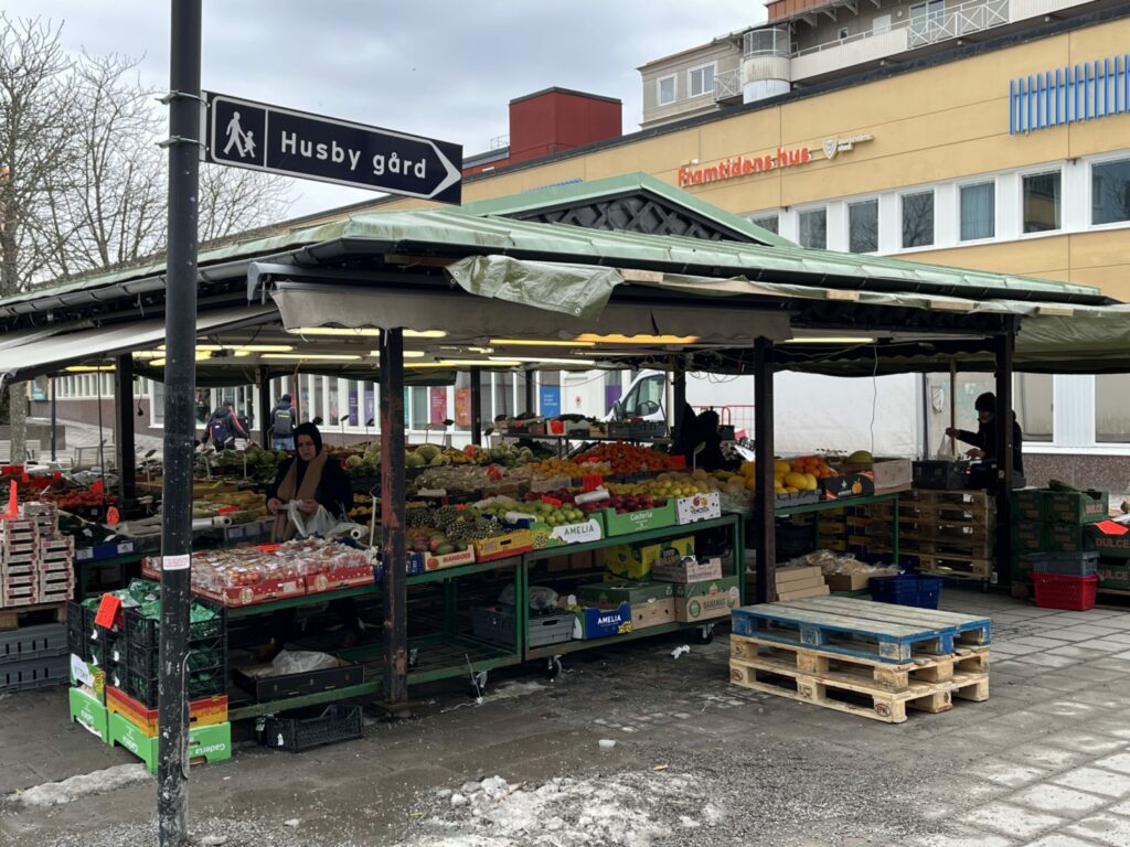 grönsaksstånd i Husby centrum och en skylt mot Husby gård