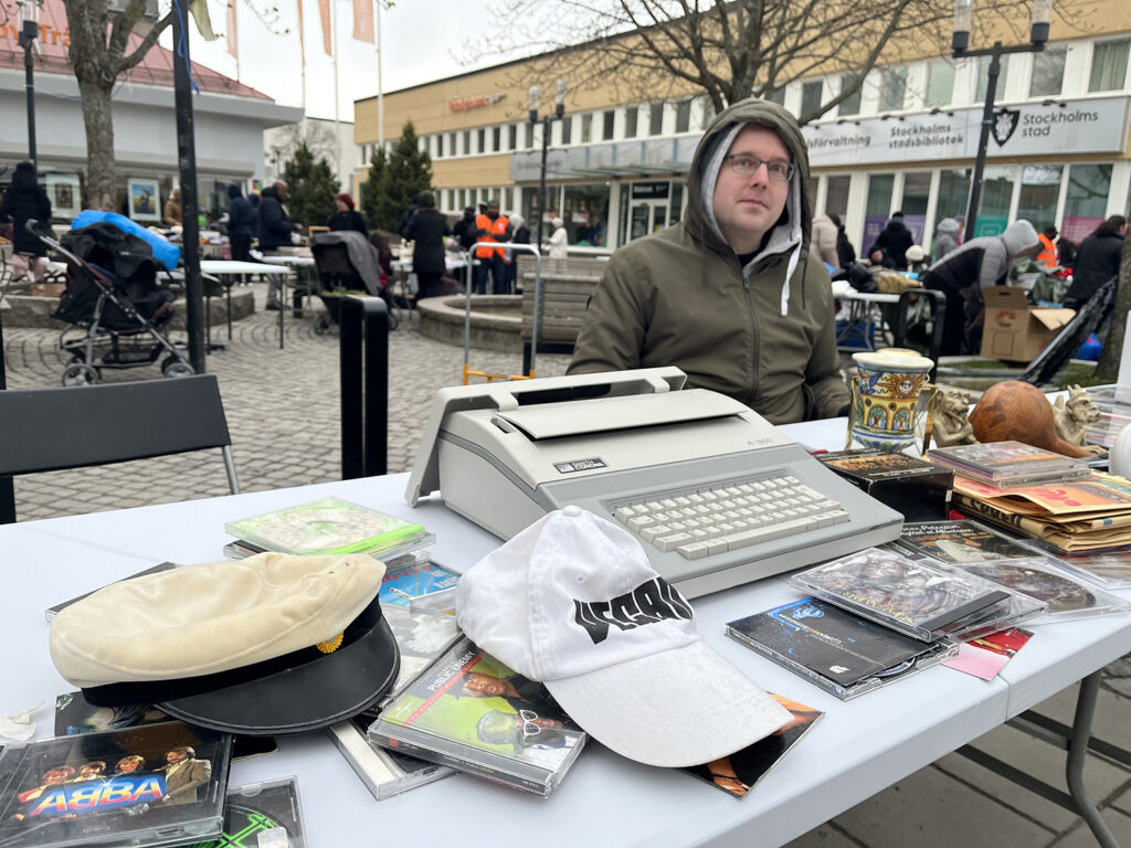 mann i grön luvjacka som säljer prylar