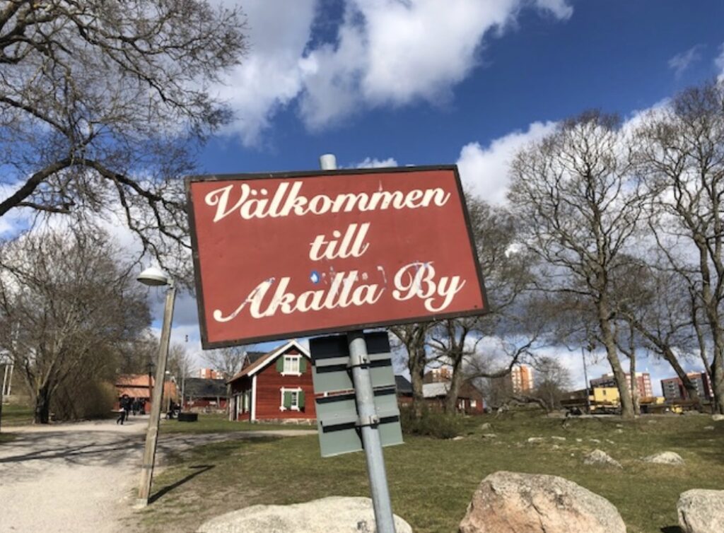 Välkommen till Akalla by står det på en skylt, vacker natur bakom-