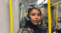 kvinna i slöja med svensk flagga bakom örat, på tunnelbanan