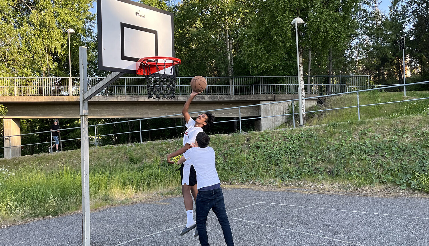 bild på två killar som spelar basket under ny korg