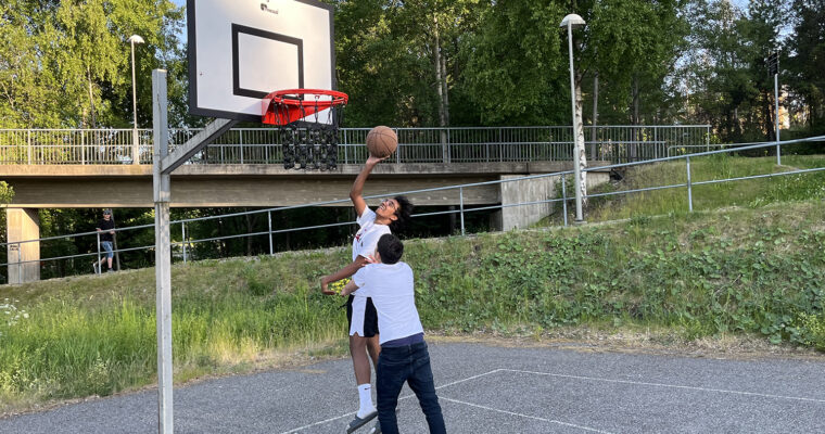 bild på två killar som spelar basket under ny korg